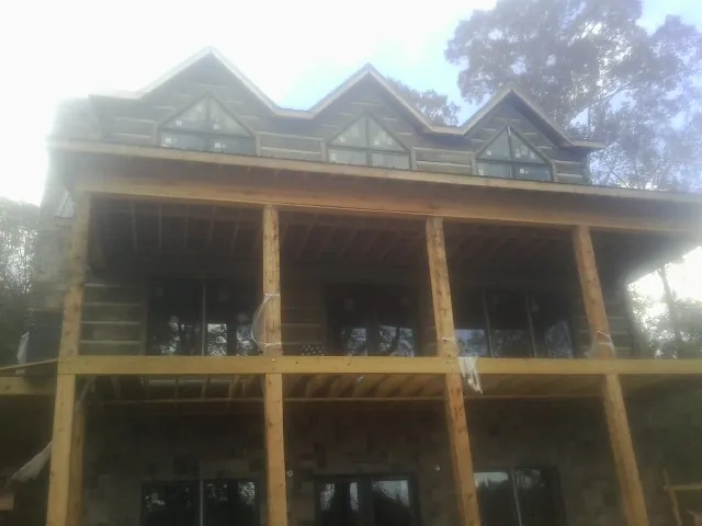 Dormers and porch framing on a large log home under construction — Roof Coating work by our crew in Taopi