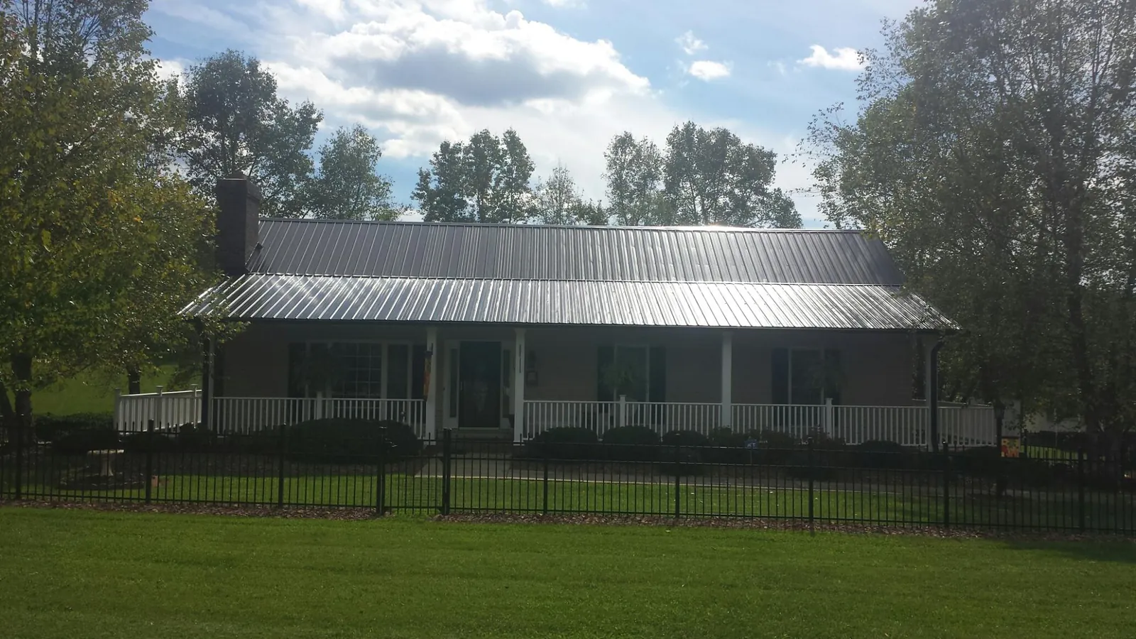 Gray metal roof on a brick ranch with a full width front porch — Gutter Guard Installation work by our crew in Taopi