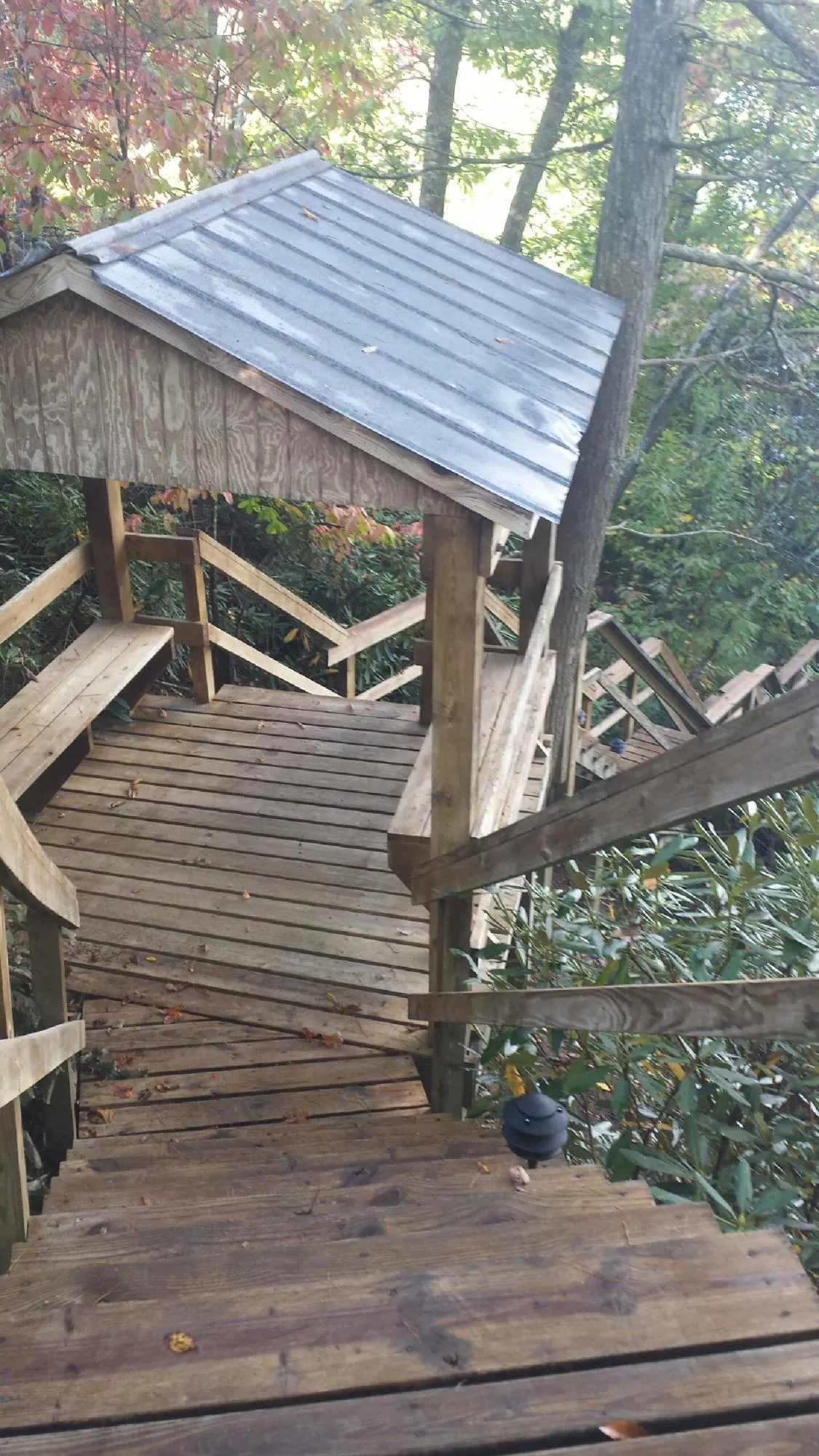 Metal roofed shelter over wooden steps on a wooded walkway — Skylight Repair & Installation work by our crew in Taopi
