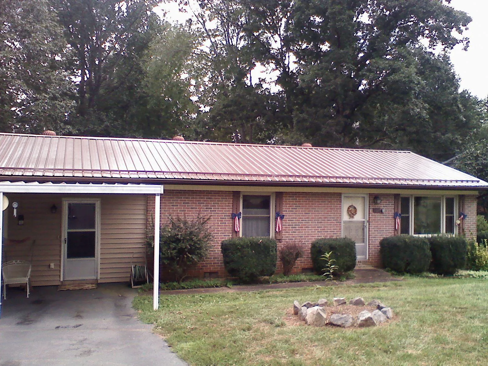 Bronze metal roof and carport on a brick ranch home — Roof Repair work by our crew in Taopi