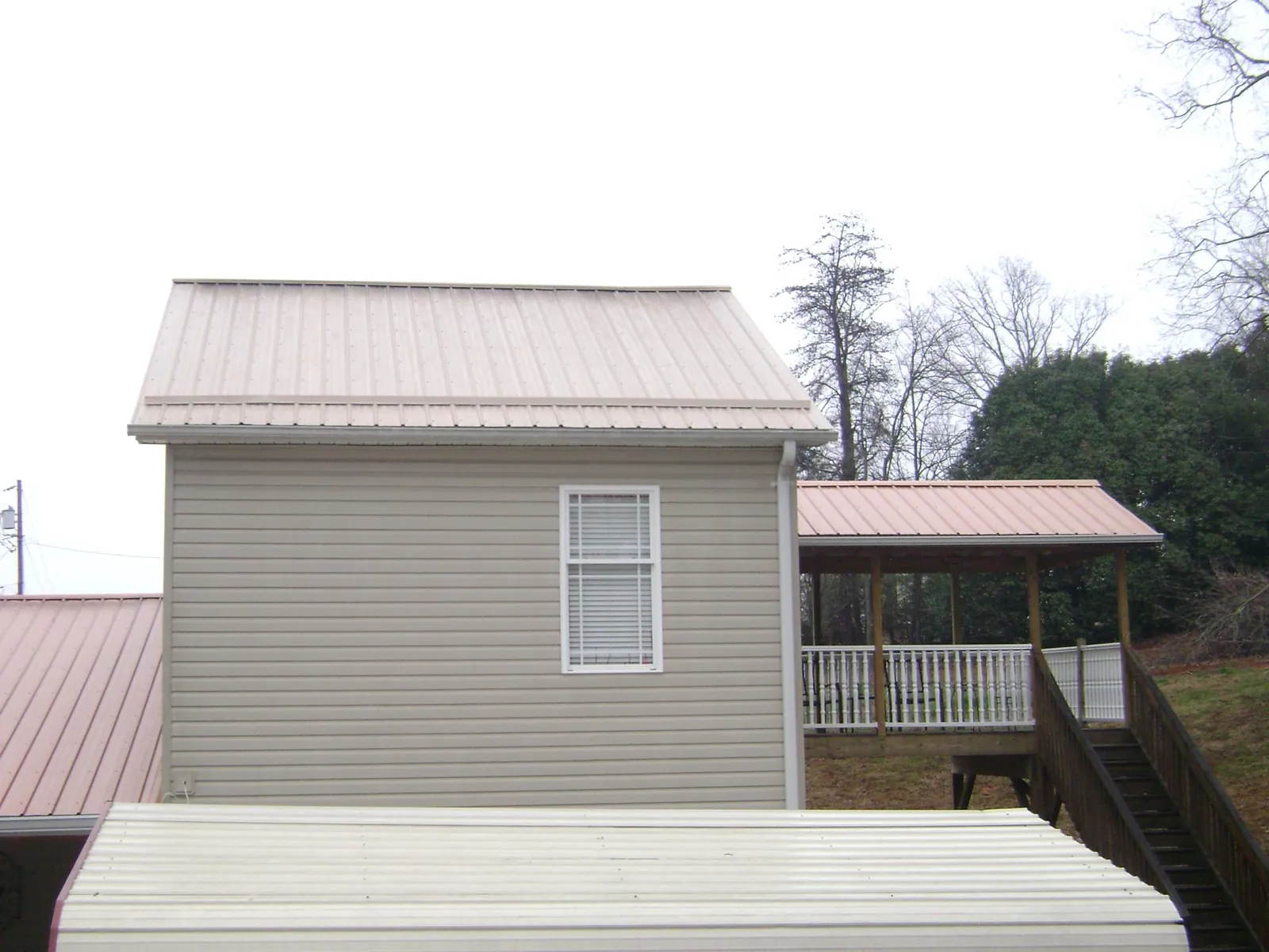 Tan metal roofs on a two story addition and attached porch, from a Roof Replacement job in Taopi